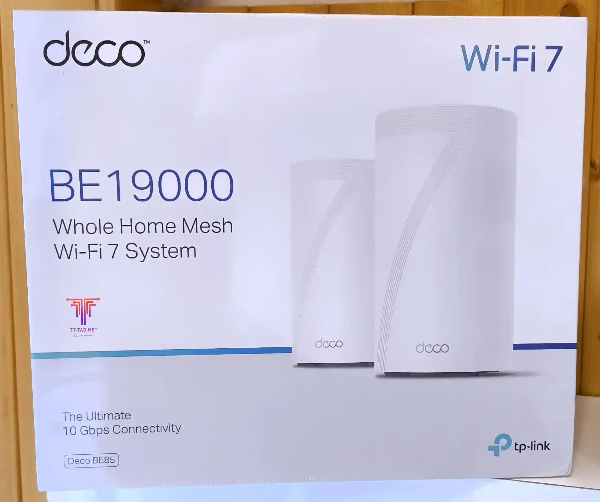 TP-Link Deco BE19000 Wi-Fi 7 mesh system packaging on a wooden surface